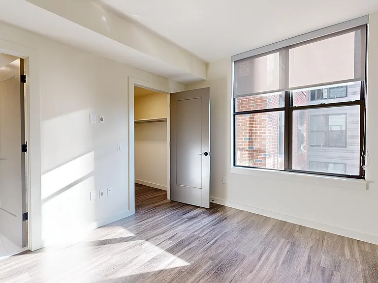 Spacious apartment bedroom with large closet, attached bathroom, and wood-style flooring.