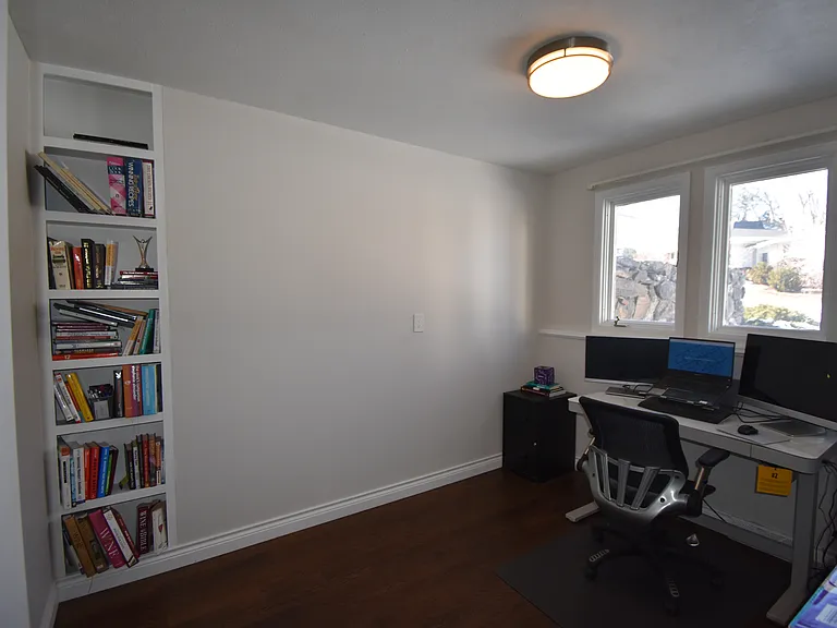 downstairs bedroom/ office with built-in bookshelf, large windows and a closet