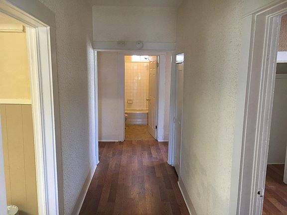 hallway to bathroom. Wide hallway. There is the smoke detector and carbon monoxide detector on beam over opening.