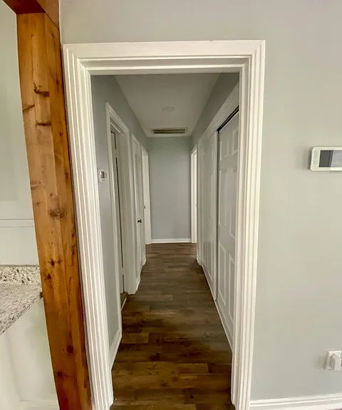 hallway leading to bathroom and bedrooms with sliding door closet across from bathroom.