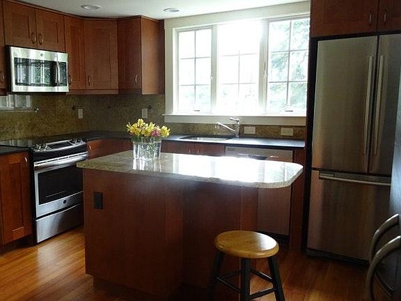 Sunny kitchen with all new appliances and stone counters with seating for two.