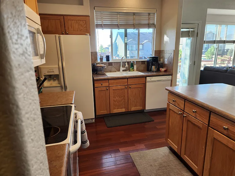Kitchen with electric stove, refrigerator, and dishwasher. Bar seating