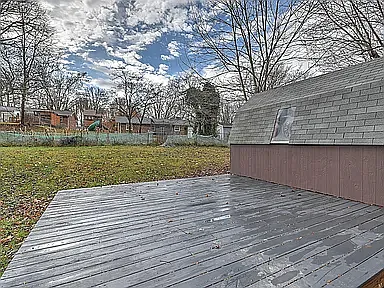 Fully painted deck with room for table seating, pots, and entertaining. The garden is now lush, green, flat grass with an in-ground fire pit.