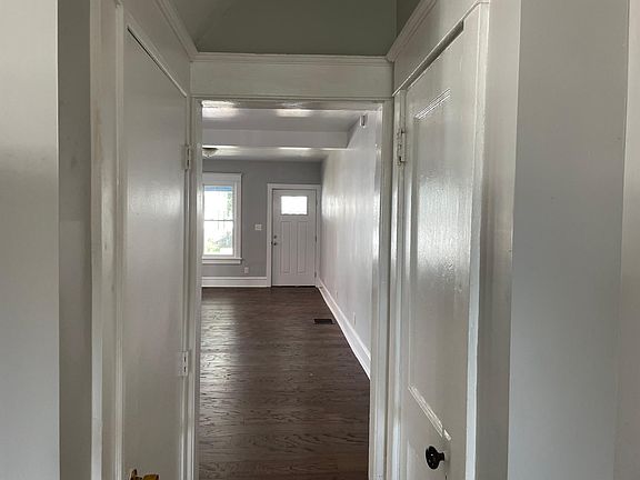 small hall between living room and kitchen. door on right is a coat closet door on left leads to the basement