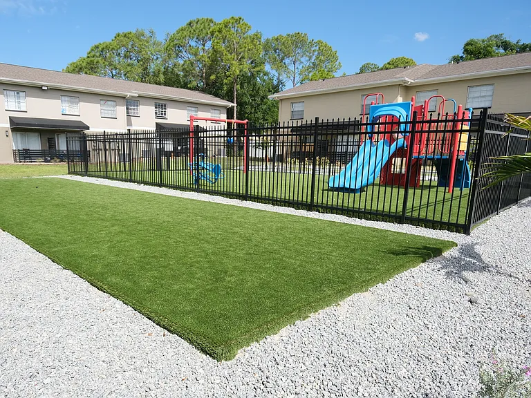 Charming apartment complex playground featuring colorful slides and swings on a lush green lawn, perfect for family fun.