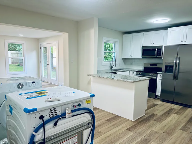 Kitchen & dining area (washer/dryer to be installed in garage). Dining area leads to large sunroom addition.