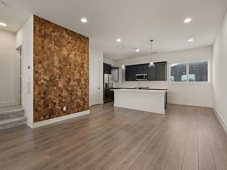 Accent wall, kitchen, and stairs up on the left.