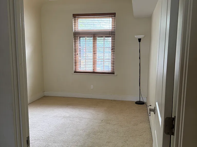 Master bedroom with carpet floows and large window.