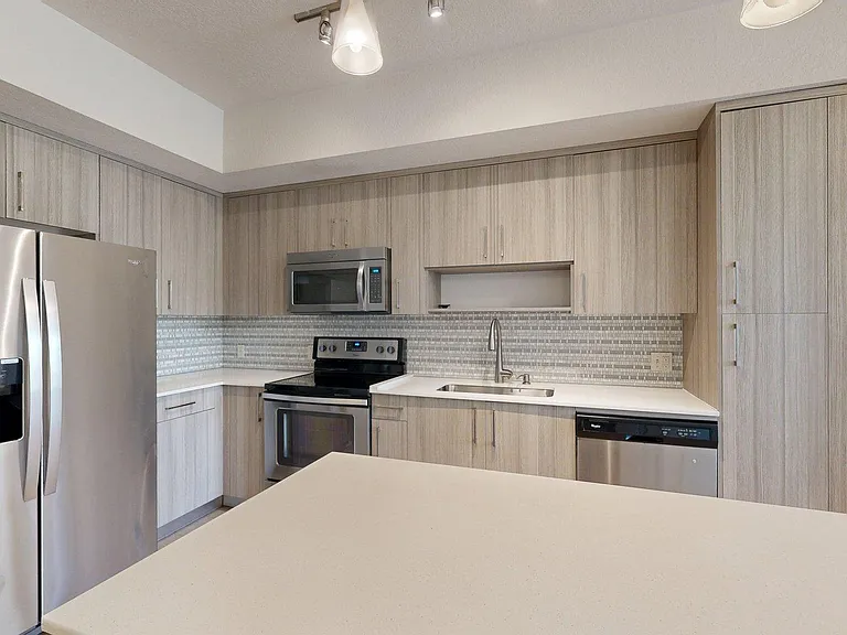 Apartment kitchen with stainless steel appliances and light counters.