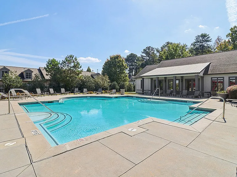Inviting outdoor pool area with crystal-clear water, surrounded by comfortable seating and lush greenery.