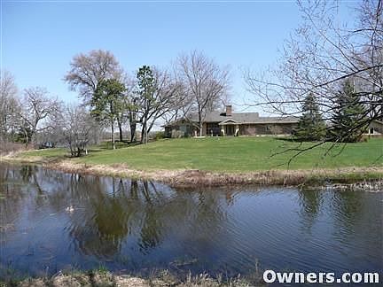 View from road - across pond - of house.