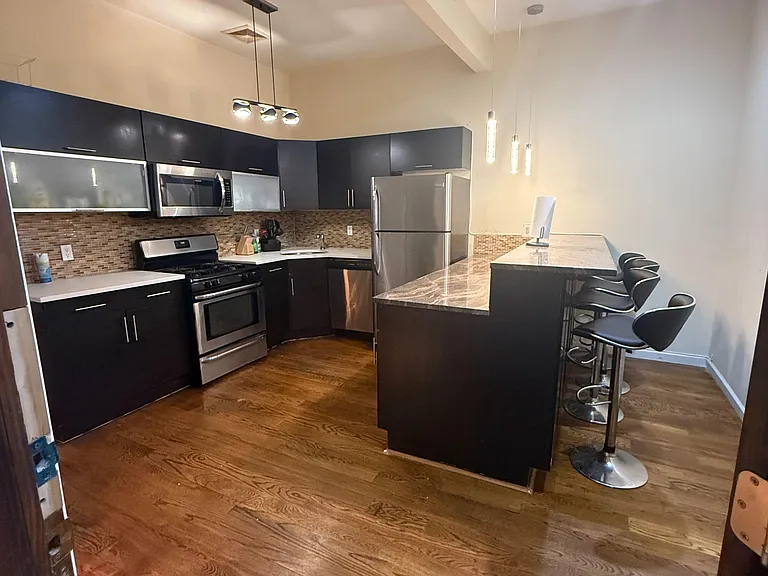 Open-concept kitchen with stainless steel appliances, ample cabinetry, and a peninsula breakfast bar with seating.