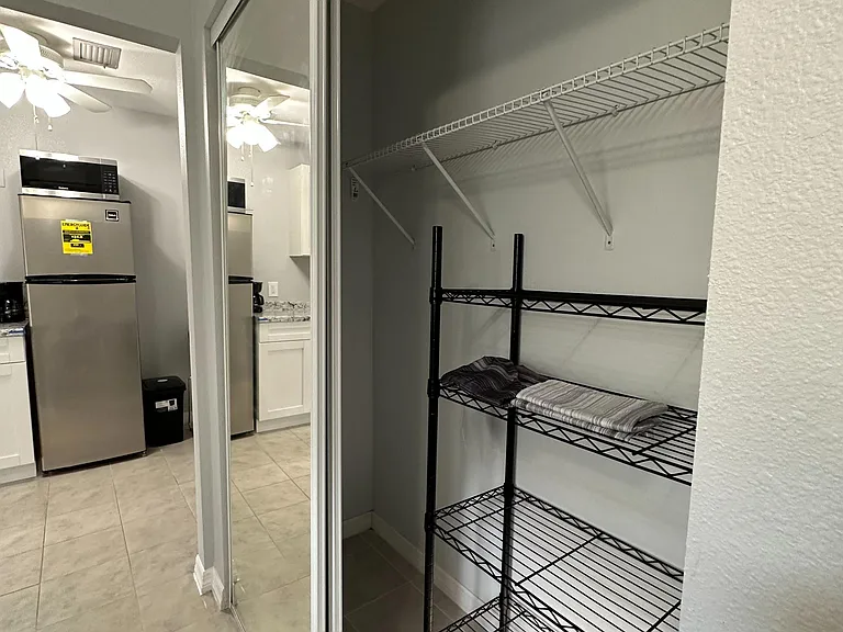 Walk-in storage closet with wire shelving and sliding mirrored doors, conveniently located off the kitchen.
