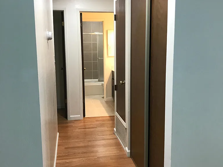 Hallway passing a closet and utility room to bedrooms