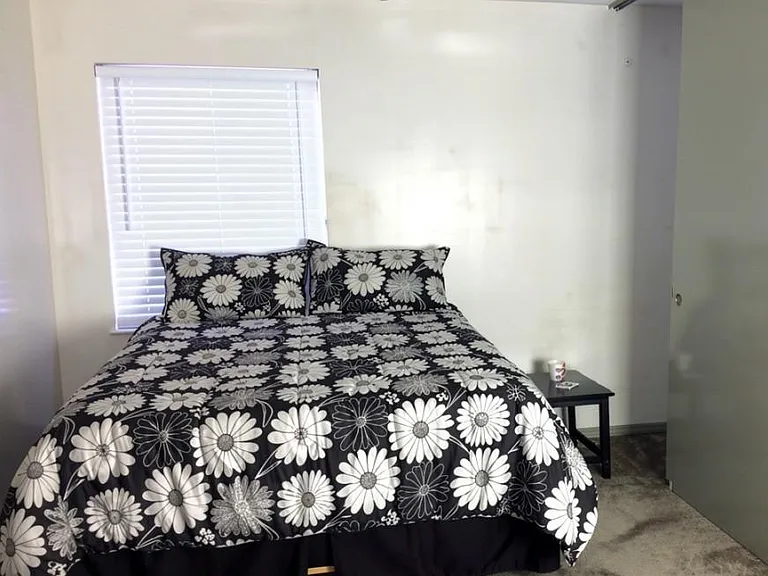 Furnished bedroom with a queen bed, ceiling fan, and a window with blinds for easy light control.