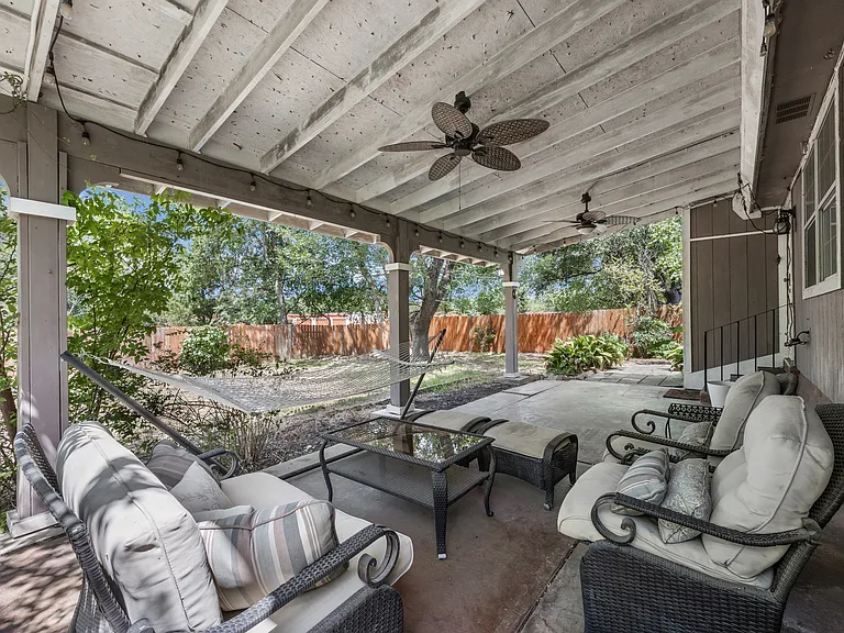 Backyard patio with string lights and ceiling fans. Patio furniture included.