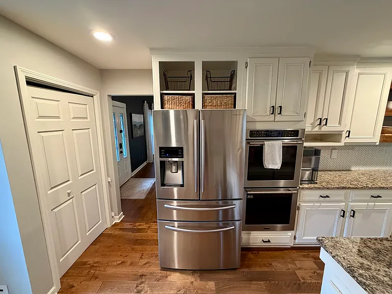 Appliances including large fridge and double ovens, as well as pantry