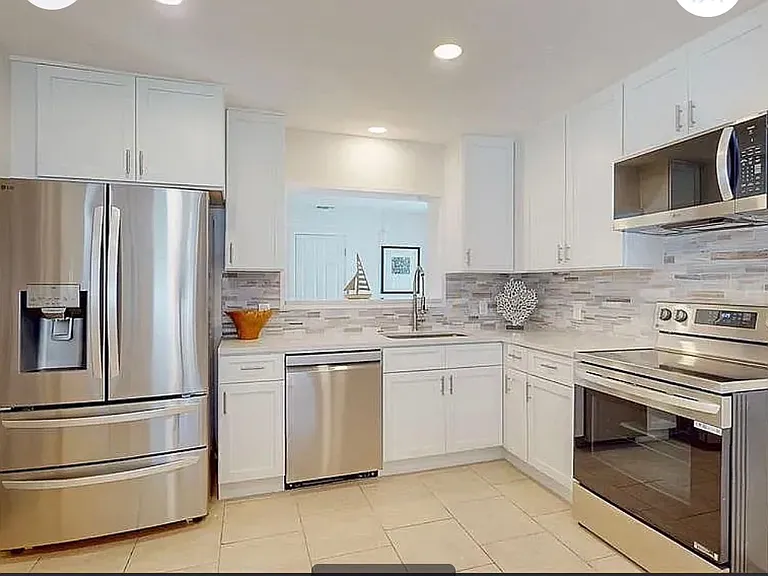 Fully remodeled kitchen with brand-new LG stainless steel appliances, white shaker cabinets, and modern tile backsplash