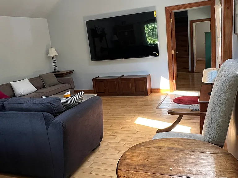 Huge living room with 85" TV and queen size sleeper couch.