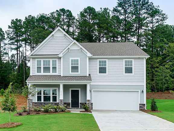 A large white house with a garage and trees in the background