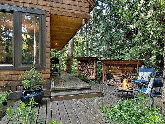 Looking toward the southwest corner of the home, the windows to the left have a sweet window seat on the interior.  Two tidy woodsheds to feed your wood stove or your fire pit tucked close to the forest.