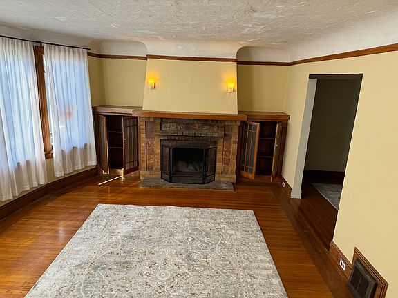 Large open front room eager to greet you and guests with proud fireplace and reddish/orange gumwood side bookcases and trimmings_Five large roundabout windows to let sunshine dazzle your spirit_