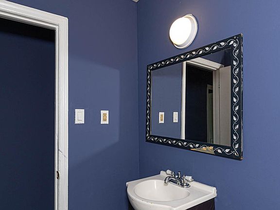 Compact bathroom vanity area featuring a single-sink cabinet, wall mirror, and overhead light for daily routines.