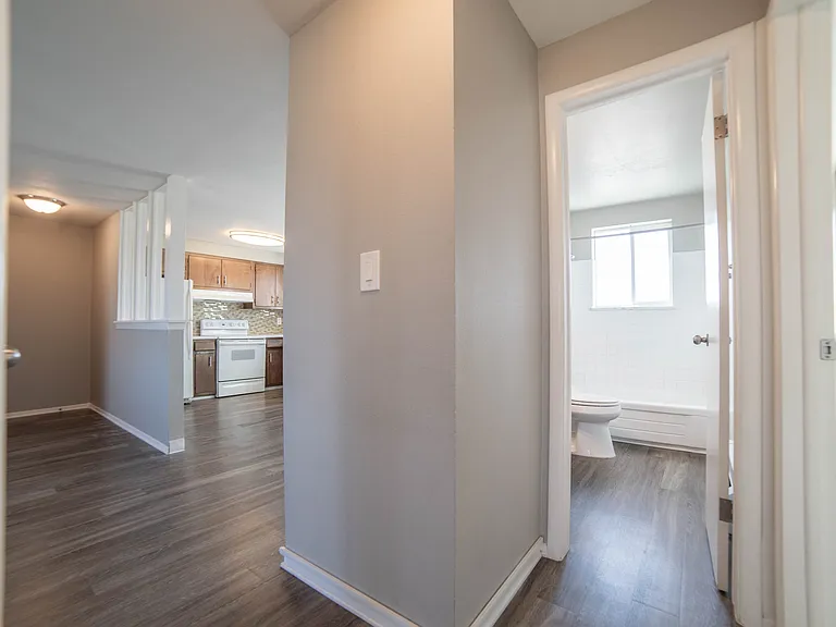 Inviting apartment interior featuring a modern kitchen with wood cabinetry, sleek hardwood floors, and a bright bathroom with natural light.