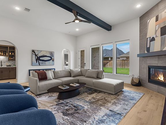 Designed for today's busy lifestyle, this family room is equipped with a gas log fireplace & stylish beam ceiling. Note the wet bar to the back left outside the media room. SOME furnishings included like this living room sofa & coffee table. Most furnishi