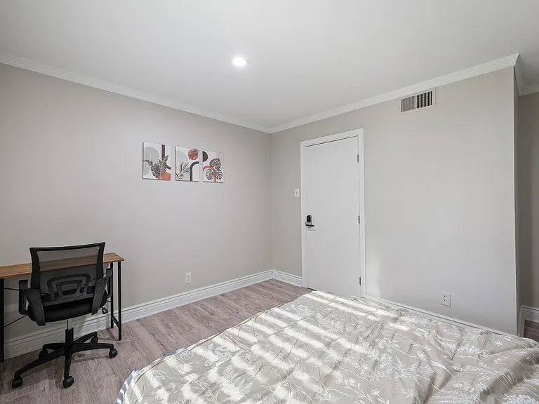Private bedroom with wood-look flooring, neutral walls, and space for a bed plus a dedicated work-from-home desk.