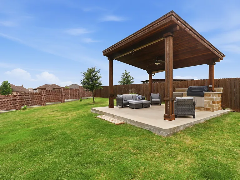 Spacious backyard featuring a Custom Outdoor Pavilion with a built-in outdoor kitchen, wood-finish ceiling, and ceiling fan
