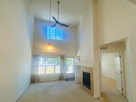 Light filled living room with ceiling fan and fireplace