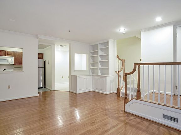 Front door to the right, living space, view of den, stairs to master bedroom on 2nd floor, half bath at bottom of stairs.