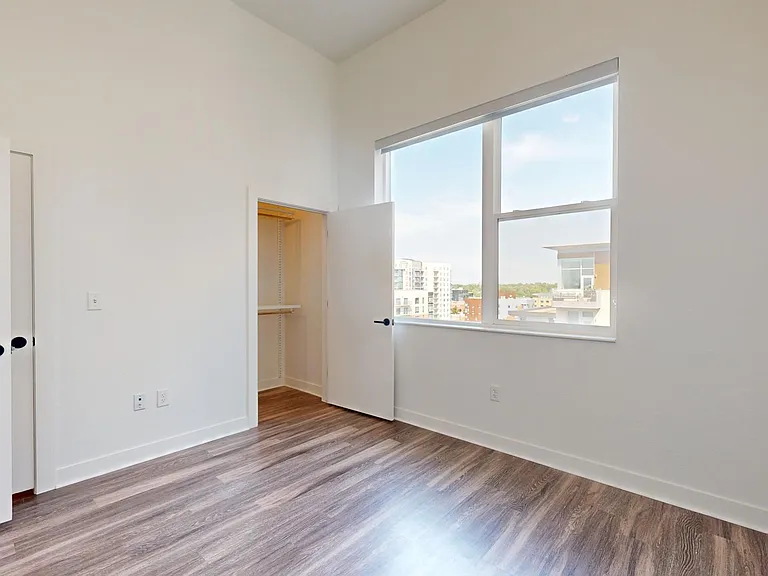 Spacious apartment bedroom with large closets and wood-style flooring.