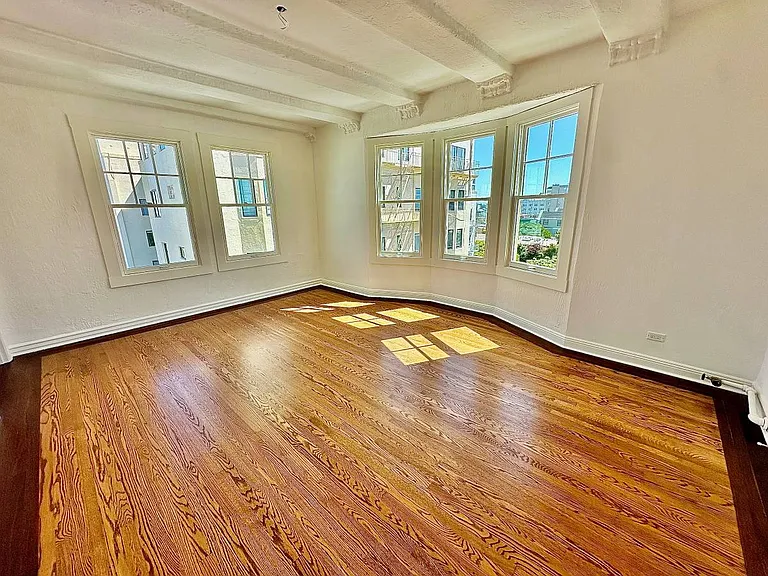 Unit #602 enormous living room with gorgeous beamed ceilings and newly refinished hardwood floors!
