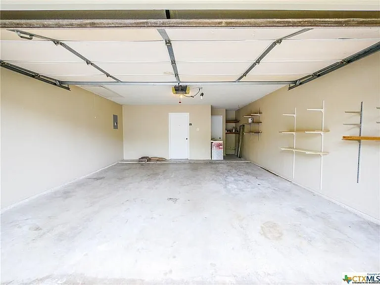 Garage with built-in storage areas, electric opener, painted walls.