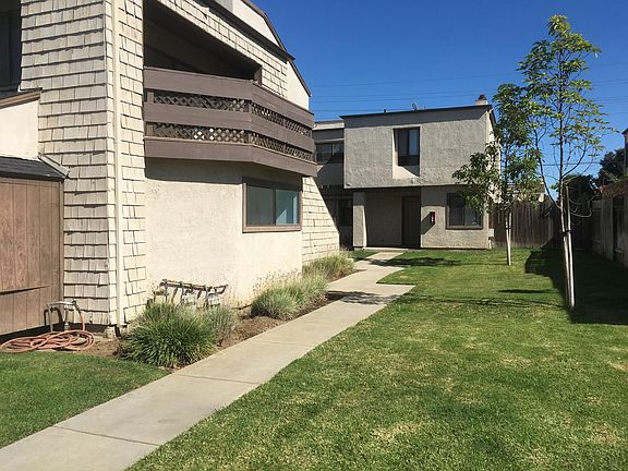 Walk path to upstairs unit. The balcony off the living room can be seen overlooking grass.