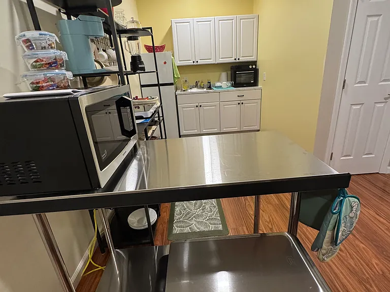 Kitchen cabinets & fridge - bakers rack on left. Microwave. Induction stovetop, Keurig coffee maker, blender, rice cooker, All in One: toaster, broiler, grill, air fryer, dehydrator, oven. Fully equipped kitchen. Trash can/recycling bin.