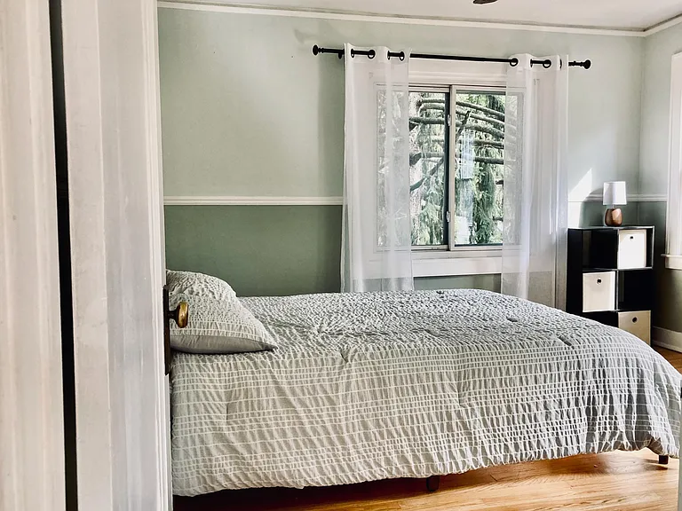 View of the second-floor bedroom, which has two exposures and wood floors. A queen bed is shown in this picture.
