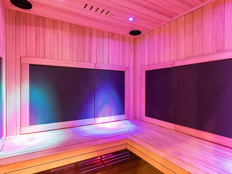 Luxurious infrared sauna with ambient LED lighting, featuring modern wood paneling and a cozy bench.
