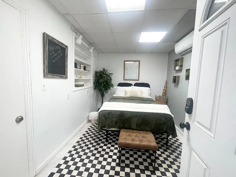 Furnished bedroom with a full bed, built-in wall shelving, and mini-split A/C for year-round comfort.
