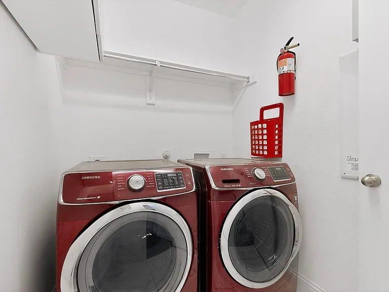 A compact utility room showcasing a side-by-side washer and dryer, with shelves above.