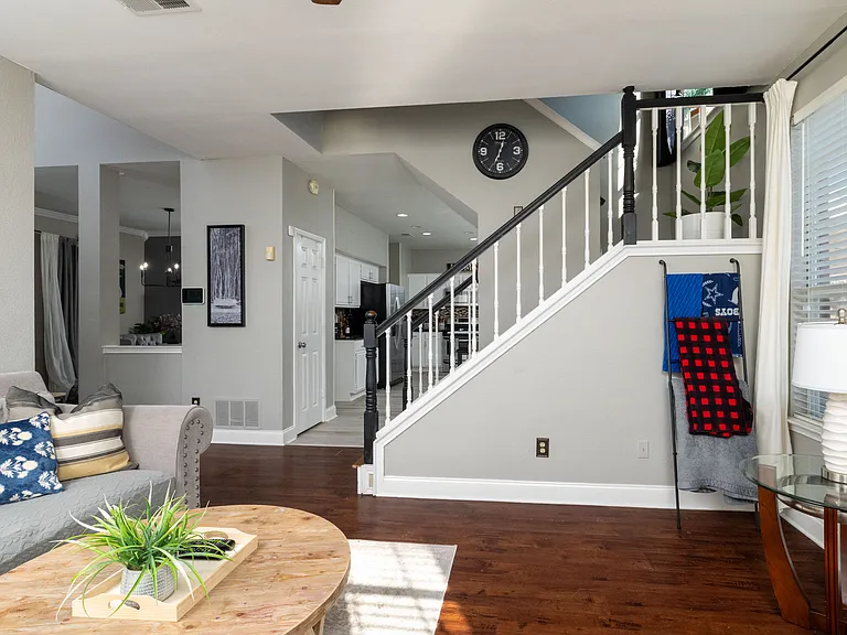 Modern open-plan living room with an elegant staircase and warm wood flooring.
