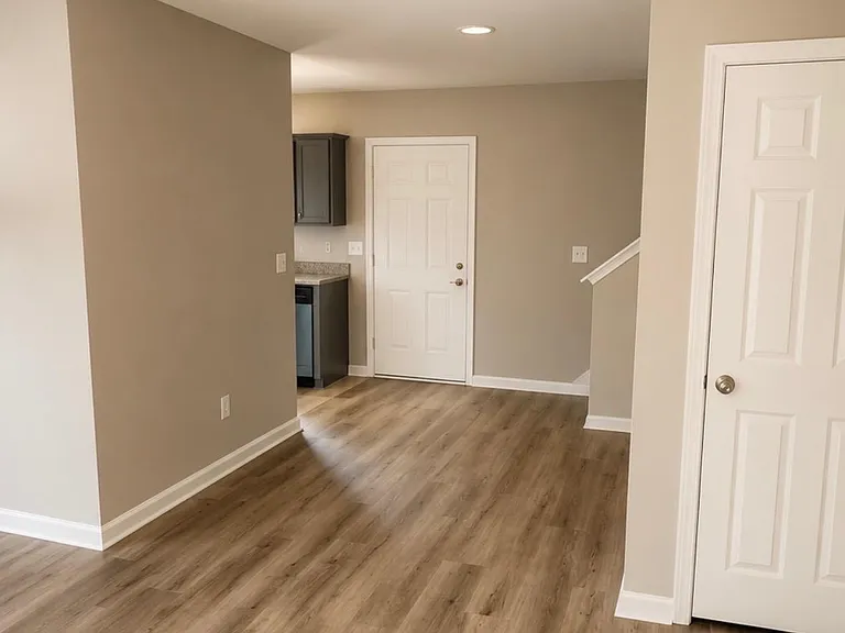 Open-concept common area with durable wood-look flooring and neutral finishes, flowing into the kitchen for easy daily living