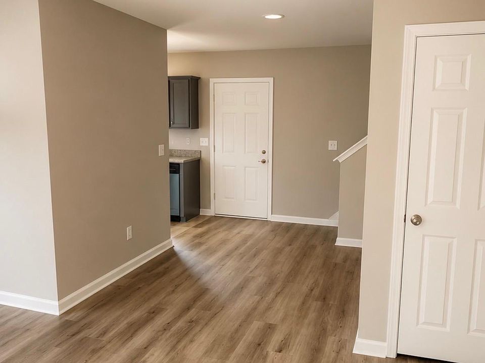 Open-concept common area with durable wood-look flooring and neutral finishes, flowing into the kitchen for easy daily living