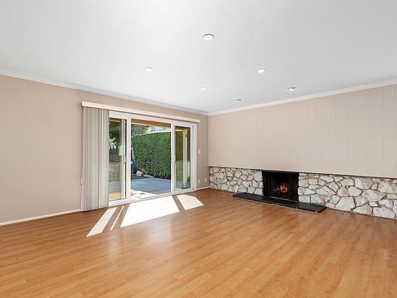 Spacious Living Room with rock fireplace, beautiful wood flooring and overlooking the backyard...