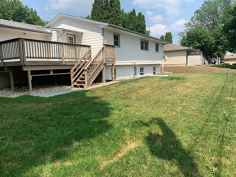 View of backyard and deck. Lower level entrance visible
