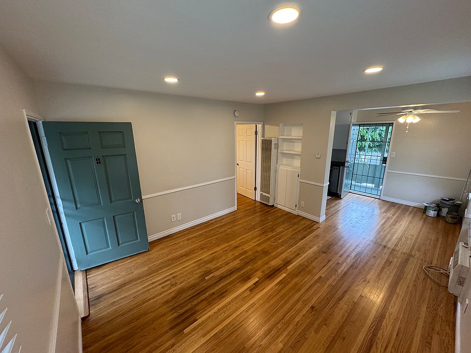 Photo taken from living room. Front door on the left, back door in the background. Bedroom is through the open door to the left and on the right the living room leads to the dining room and into the kitchen.