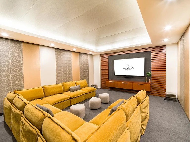 A private theater room with plush seating, layered lighting, and a large display, offering a comfortable space for movie nights or small gatherings.