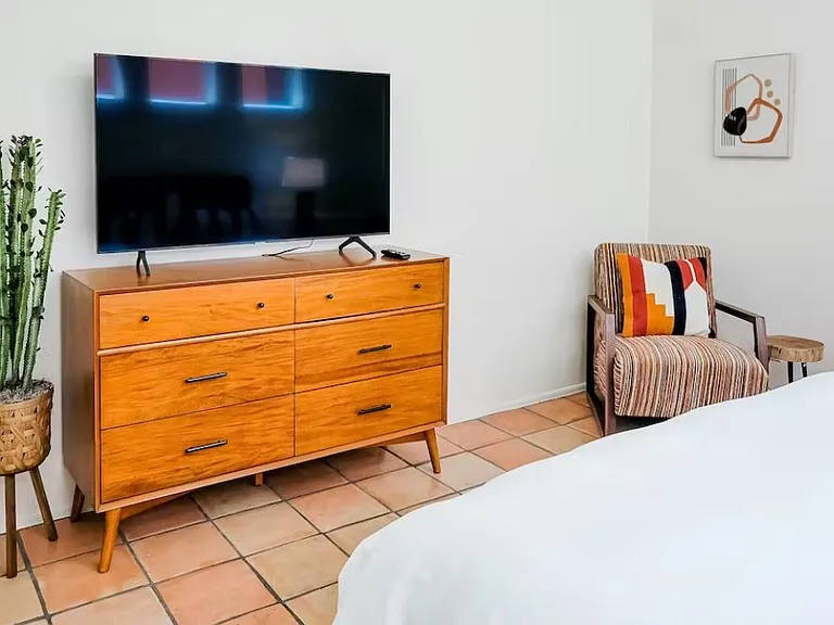 TV in primary bedroom with walk-in closet, dresser, chair and desk with chair.